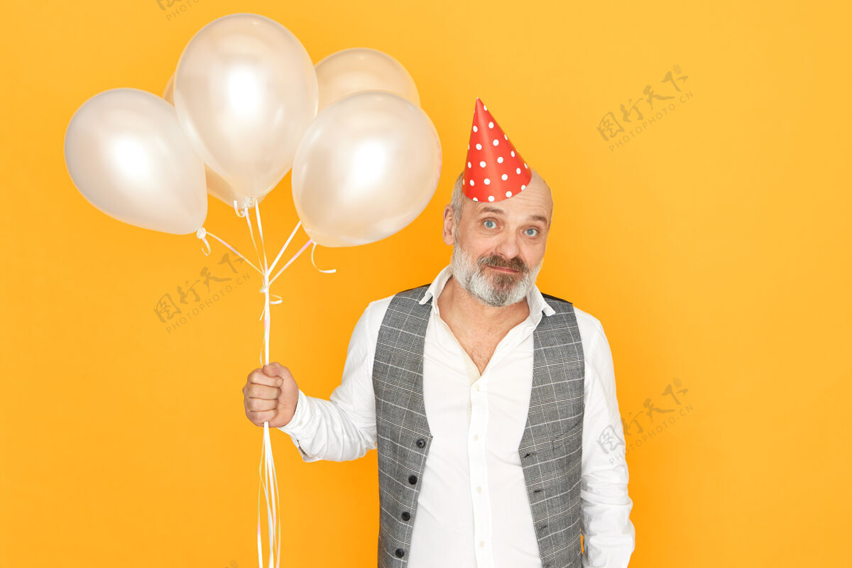 成熟一个留着灰胡子的成熟男人在庆祝结婚纪念日一个英俊的 没刮胡子的男性退休者手持氦气球在生日派对上玩得很开心的肖像成人庆祝氦