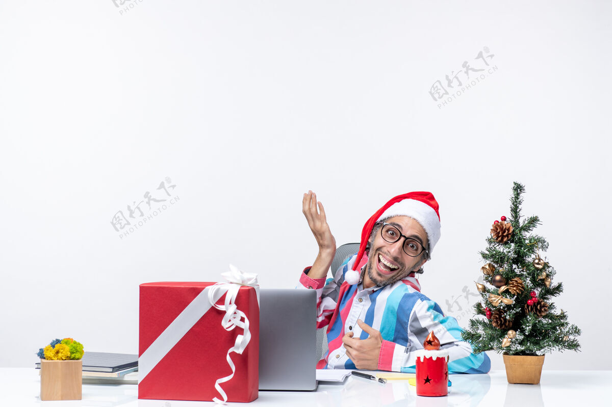 风景正面图：年轻的男工人坐在他工作的地方 背景是白色的坐着礼物微笑
