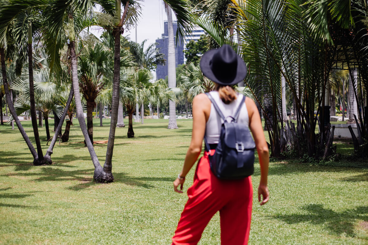热带快乐女人背着背包环游曼谷 在绿草如茵的热带公园里享受美丽的晴天户外人休闲
