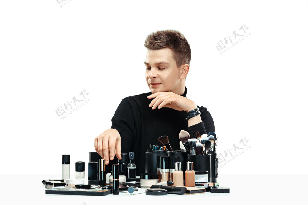 微笑专业化妆师与工具隔离在白色工作室的背景下男性在女性profesion性别平等的概念男性护理容貌