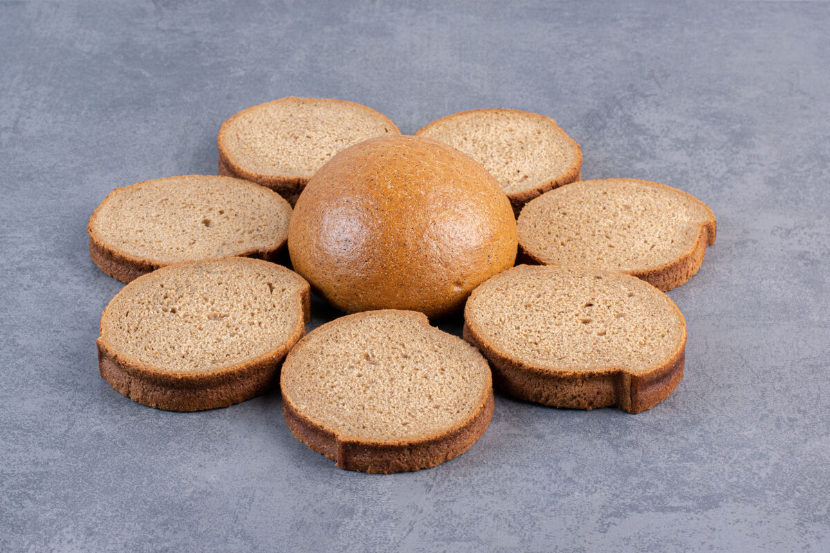 烘焙食品一圈棕色的面包片围绕在大理石上的一个小面包上饮食面粉烘焙