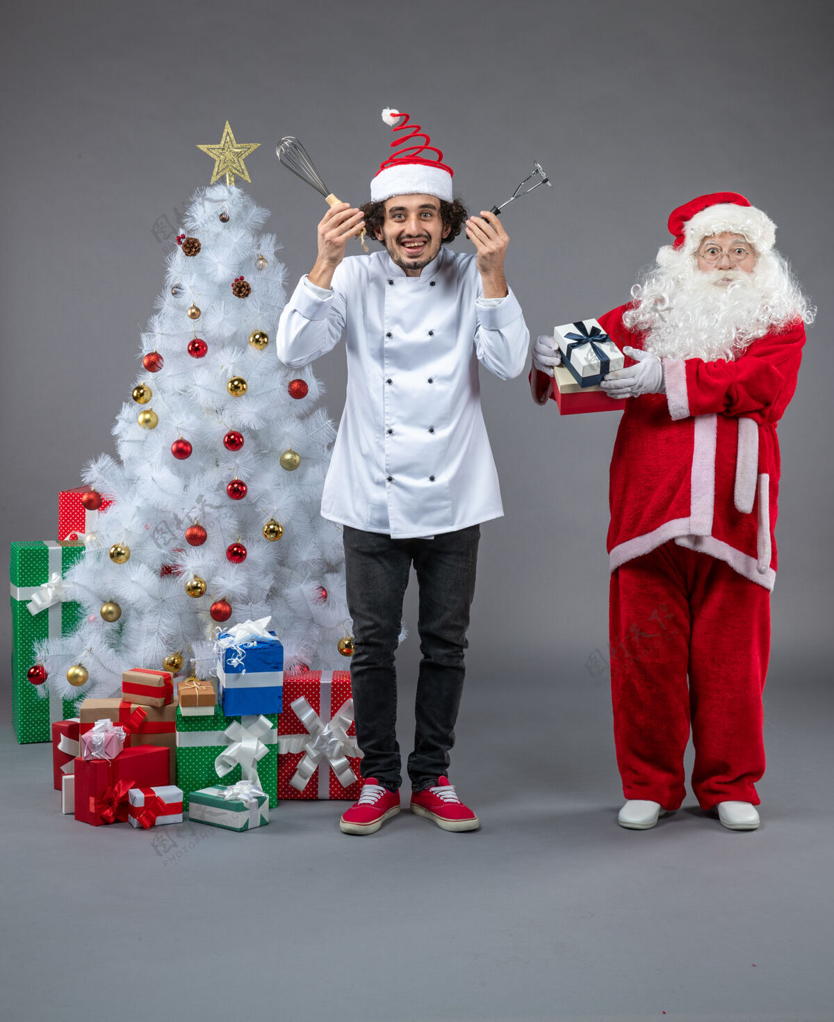 庆祝圣诞老人和男厨师在灰色墙上围着圣诞礼物的正视图礼物快乐圣诞老人