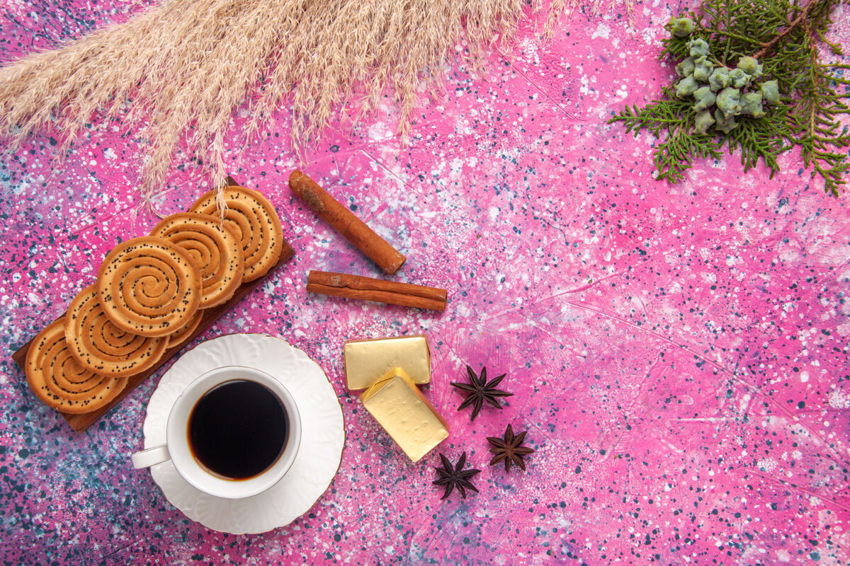 糖在浅粉色的桌子上放一杯茶 上面放着饼干和肉桂肉桂顶部曲奇