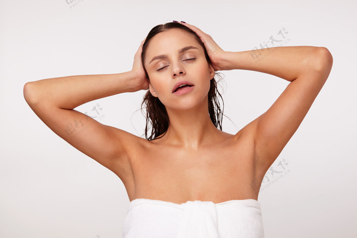 护肤年轻漂亮的黑发女性 穿着浴巾 头发湿漉漉的 手举着头 眼睛紧闭着心情美丽毛巾