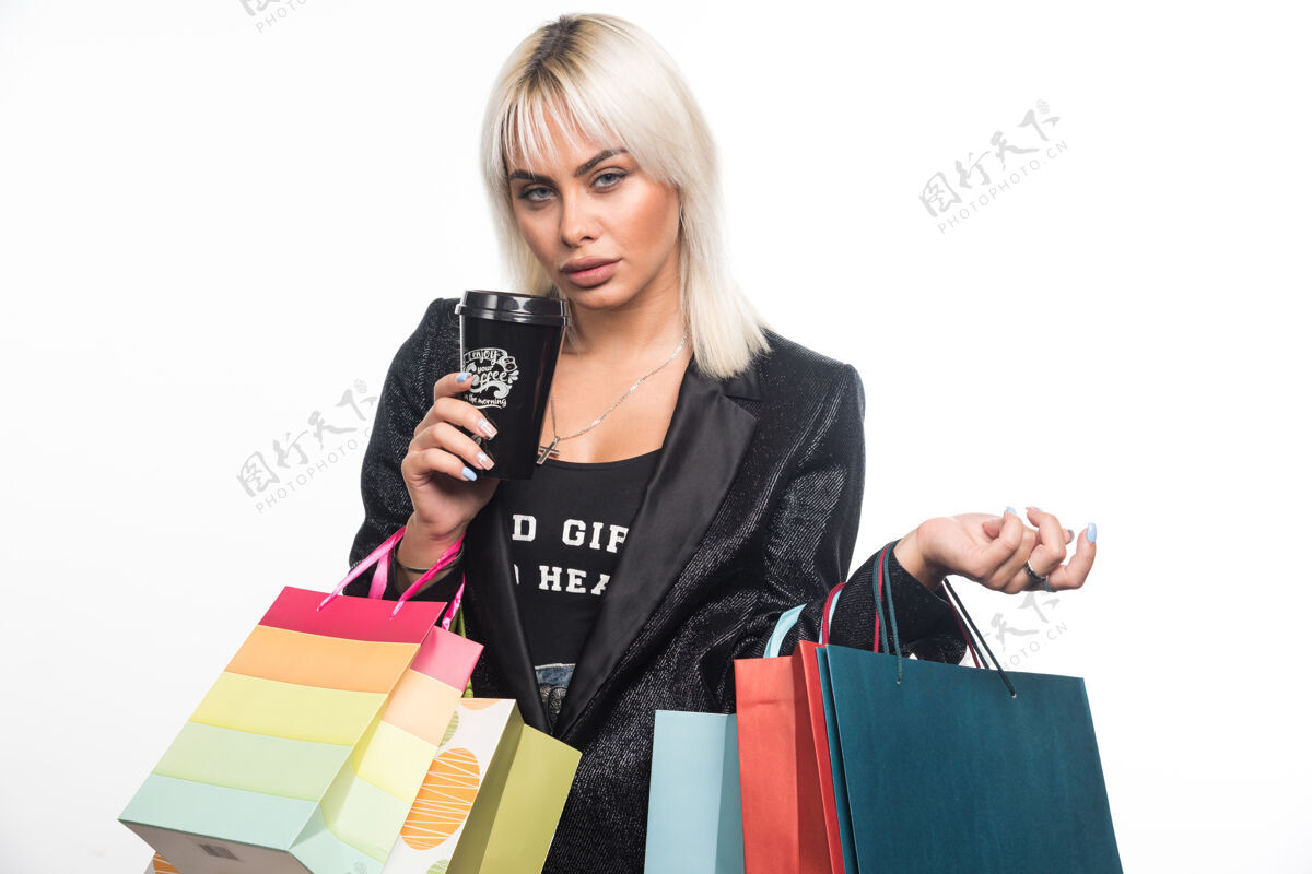 购物年轻女子手持购物袋和白色背景的杯子高品质的照片女性休闲购物者