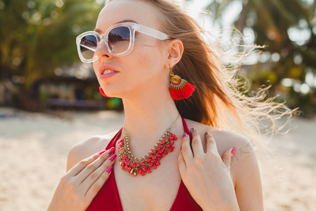 女人年轻漂亮的金发女人穿着红色泳衣 戴着太阳镜在沙滩上晒太阳年轻性感脸