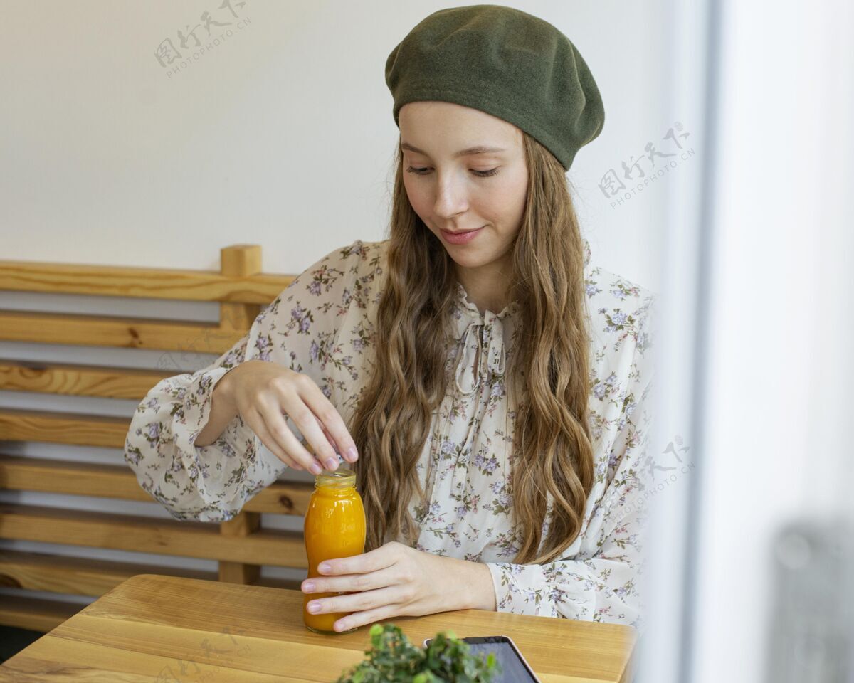 美味坐在桌边拿着新鲜果汁瓶的女人水平健康食品美味