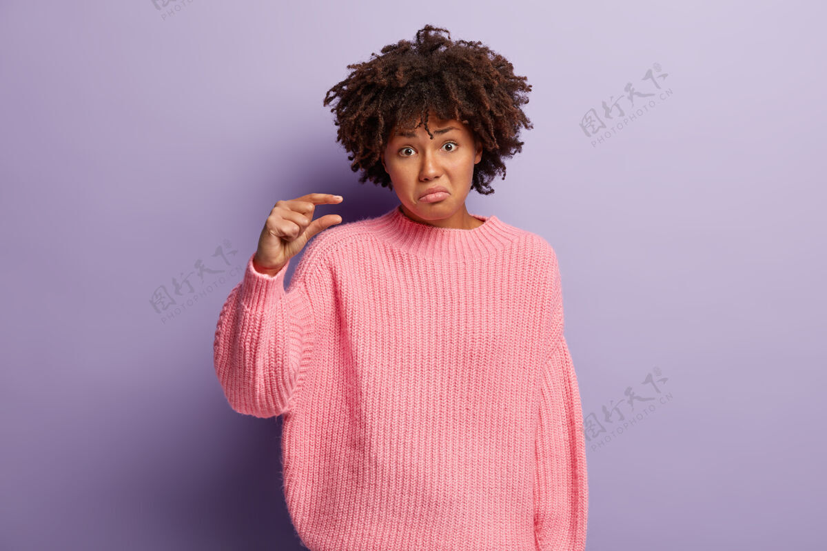 超大我需要多一点不满意的年轻非洲裔美国妇女穿着粉色针织毛衣 笑眯眯的脸人类测量数量