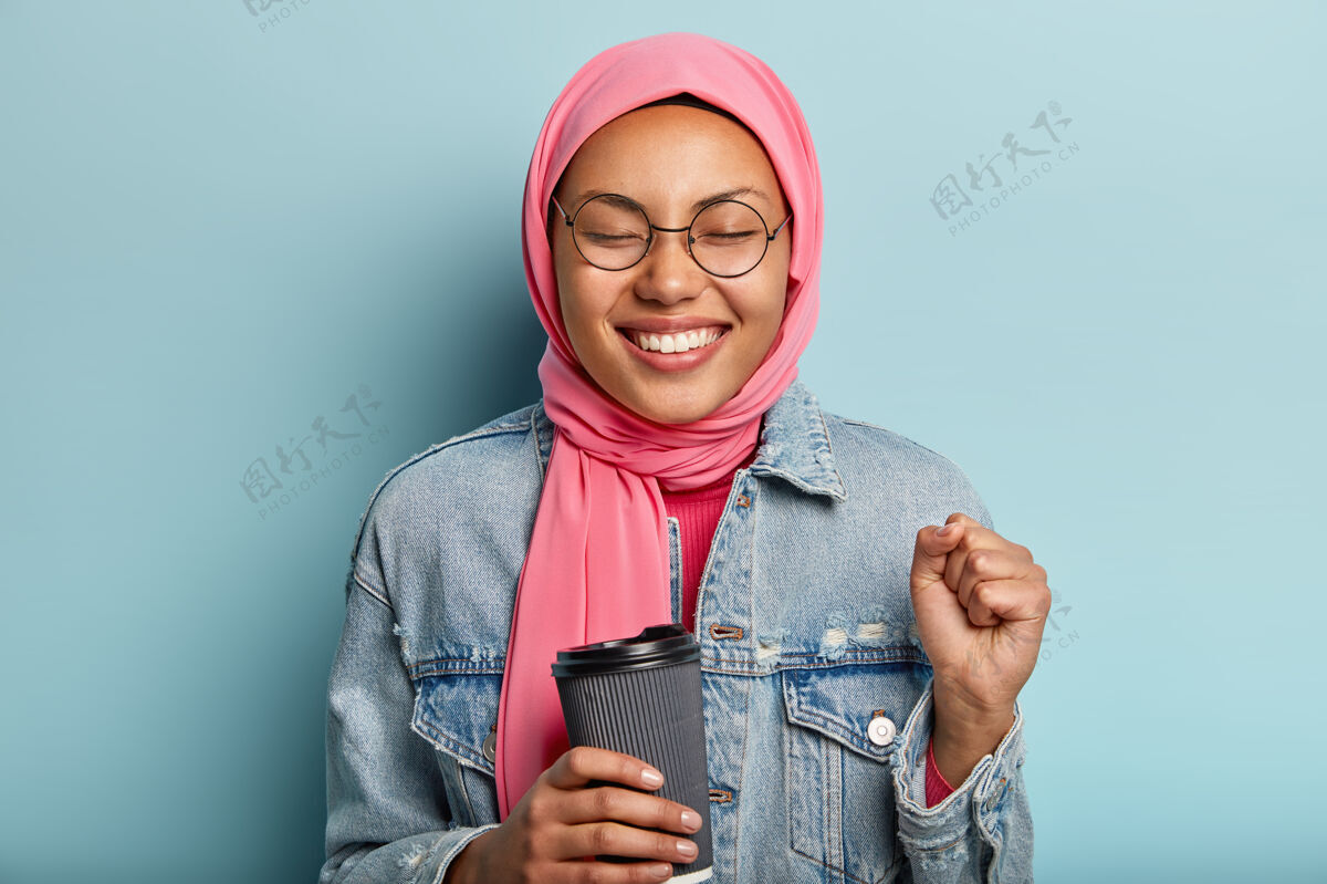 握紧乐观可爱的穆斯林女子握紧拳头 闭上眼睛从高兴拳头愿望饮料