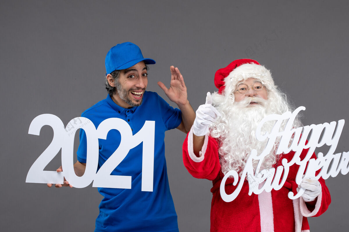 前面圣诞老人与男信使举行和新年快乐和2021年板灰墙的正面视图男信使肖像