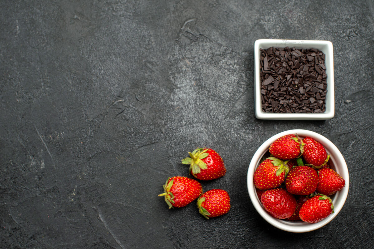 多汁顶视图：一对令人愉快的情侣 在黑暗的表面上放着巧克力和成熟的草莓 空间宽敞可食用浆果表面
