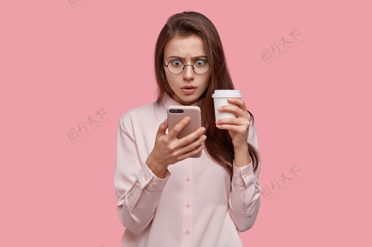 电子惊讶的黑皮肤女人的照片在手机屏幕上以惊愕的表情看着 有问题 收到了不愉快的消息震惊吓人咖啡