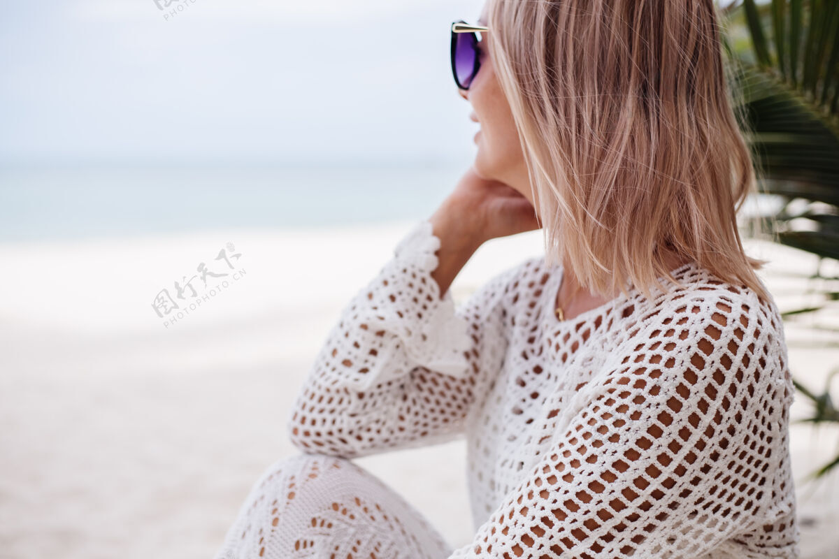 海滩沙滩上穿着白色针织衣服的女人服装魅力女性