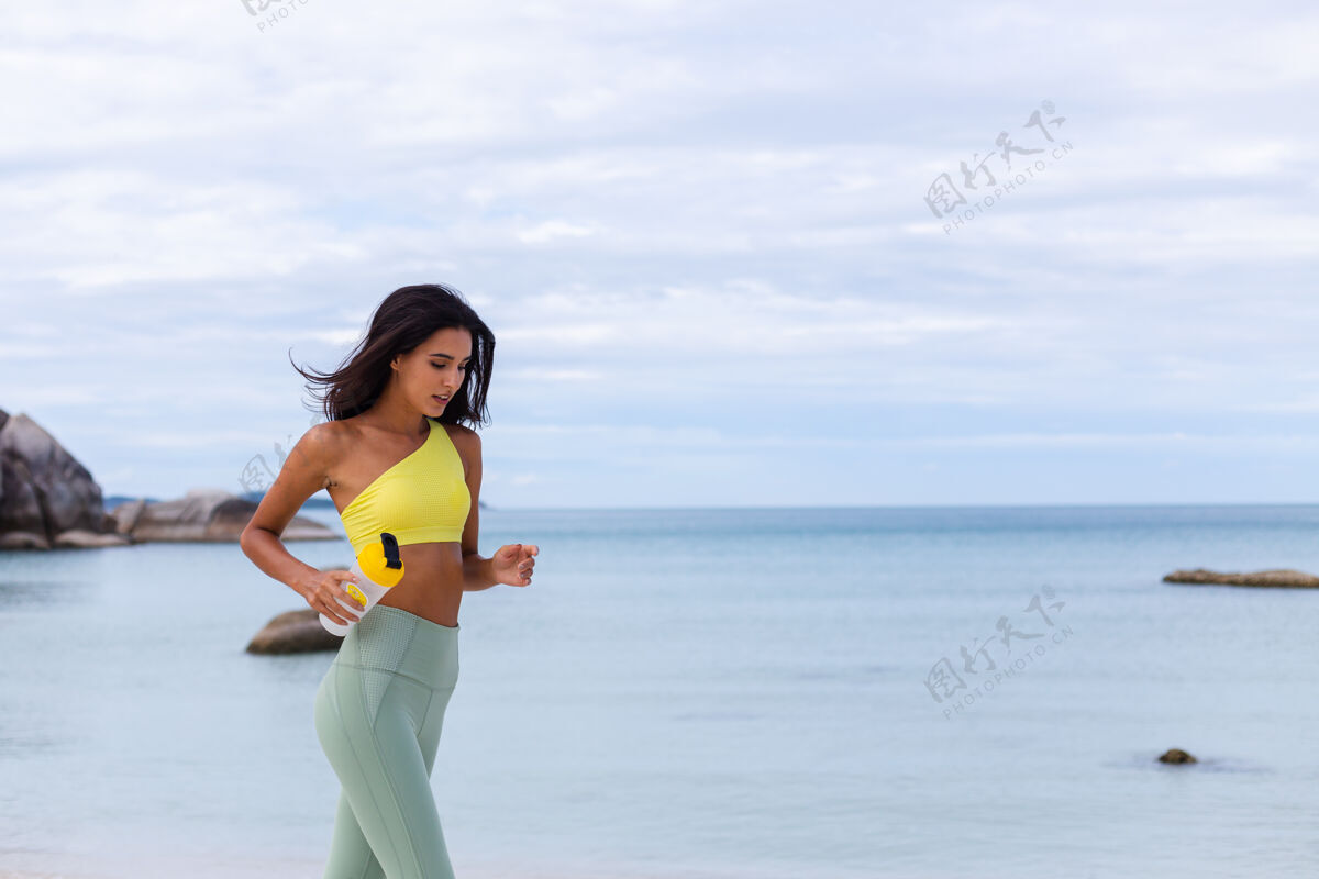 人海滩上穿着五颜六色运动服的迷人年轻女子美丽锻炼女性