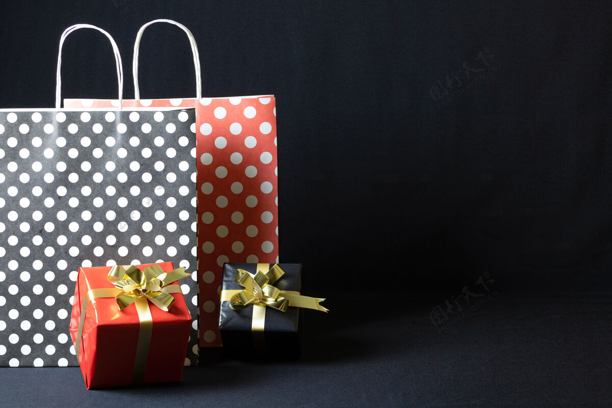 传统波尔卡圆点纸袋与圣诞礼品盒隔离在一个黑暗的背景十二月点波尔卡