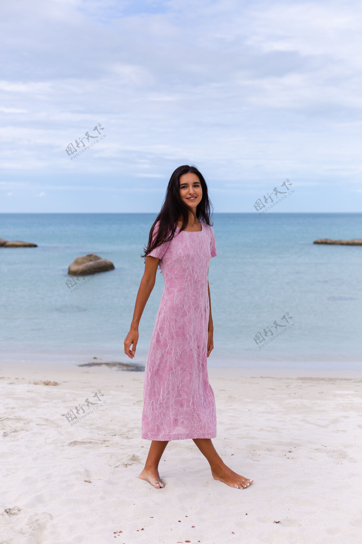 快乐一个年轻浪漫的女人 留着长长的黑发 穿着裙子 在沙滩上微笑着 笑着 一个人度过了一段美好的时光沙滩优雅美丽